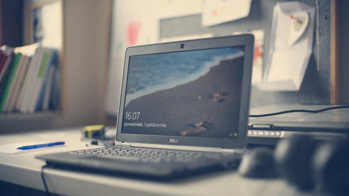 A contemporary workspace featuring a Dell laptop, books, and stationery on a desk, reflecting modern office essentials.