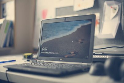 A contemporary workspace featuring a Dell laptop, books, and stationery on a desk, reflecting modern office essentials.