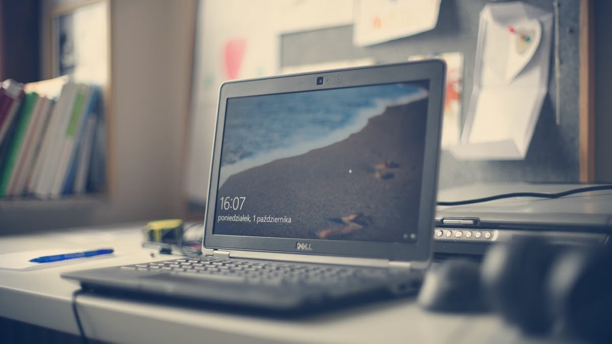 A contemporary workspace featuring a Dell laptop, books, and stationery on a desk, reflecting modern office essentials.